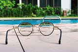 looking at a pool from a round lenses glasees in a summer atmosphere, vegetation in the background
