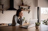 Smiling woman looking at laptop in kitchen