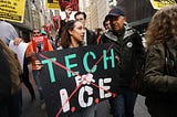 A woman holds a sign with “Tech for I.C.E.” crossed out in a protest against tech involvement in immigration enforcement.