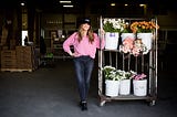 Christina Stembel stands next to various flowers in their warehouse.