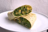 Chickpeas and lettuce shimmering with a creamy caesar dressing, stuffed into a large tortilla folded wrap-style.