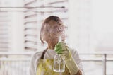 Woman spraying cleaning product in the air, obscuring her face.