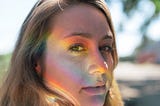 Woman with rainbow light on face.