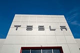 Low-angle view of the facade of Tesla Motors dealership with logo and sign in Pleasanton, California.