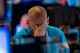 A photo of a trader wiping his eyes as he watches stock prices at the New York Stock Exchange.