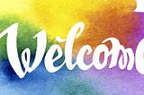 Rainbow watercolor background with white letters saying Welcome.