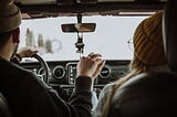 Man behind the steering wheel with woman in passenger’s seat.