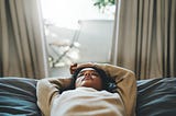 Black woman lying down with eyes closed.