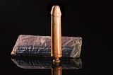 Photo of a highly polished dildo made of ivory and a cloth bag.