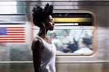 Black woman with eyes closed as subway passes by.