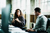 A woman discusses her idea in a meeting with a male colleague.