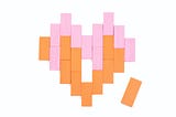 Orange and pink rectangular blocks arranged in the shape of a heart with one piece missing (an orange one next to the heart)