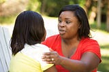 Black mother talking to her daughter outside.