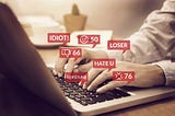 Hands typing on a laptop, surrounded by transparent red popups bearing negative words/reactions.