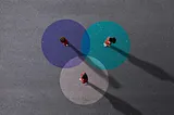 3 people facing each other standing on painted venn diagrams