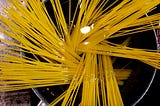 An overhead view of uncooked spaghetti in a pot of water.