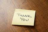 Thank you Post-it note on a wooden desk.