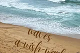 White-capped waves washing onto a sandy shoreline with the words, ‘waves a-wish-wash’ superimposed on the sand.