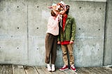 Couple kissing behind bouquet of flowers.