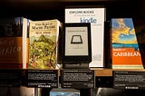 A photo of a bookshelf at an Amazon Books store where a Kindle is displayed next to the books.