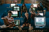 Photo of a group of kids sitting next to old school computers