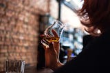 Woman holding a drink at a bar alone.