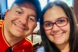 A smiling selfie of a man and woman. He is wearing a soccer shirt of the Spanish national team.