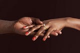 Closeup of a Black woman’s hand with an engagement ring.