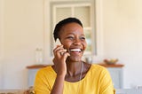 A woman laughing while talking on phone.
