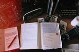 A desk with 2 notebooks, a framed photo, a typewriter, and a pencil bag. The photo has some light leak and looks vintage.