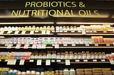 Grocery store shelf lined with bottles and boxes, under a sign labelled “probiotics and nutritional oils”