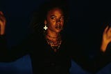 Screenshot of Rachel True from “The Craft.” She is wearing black and many necklaces.