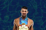 A picture of Michael Phelps, the most decorated Olympian swimmer of all time, wearing and holding all the medals he’s won over the span of his career.