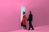 Interracial couple walking through a door in a pink wall, holding hands.