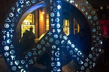 Symbolic Peace sculpture by artist, Michael Rosenblatt, 10-foot peace sign, with cultural and religious symbols illuminated at night | photography | pockett dessert