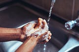 A close up hand washing in the kitchen sink.
