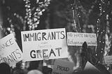 A black and white photo of people holding up hand made signs in support of immigrants and immigration.