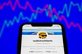 WallStreetBets forum on the Reddit displayed on a phone screen and a illustrative stock chart in the background