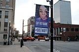 A street banner with an image of Breonna that says “SAY HER NAME BREONNA TAYLOR #BREEWAYY.”