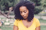 An anxious woman looks down while at the park.