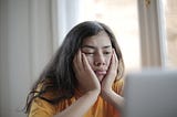 A woman staring frustrated at her laptop screen