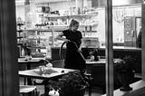 Woman in restaurant after closing, vacuuming under a table.