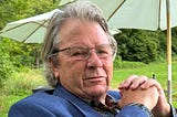 Headshot of George Phillips, outdoor umbrellas and a grassy expanse in the background