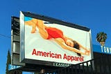 An American Apparel Ad with a woman in a red, single-piece swimsuite