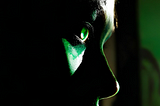 A shadowy face staring on with hungry jade-green eyes.