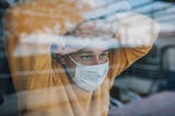 Man in quarantine wearing a mask and looking through the window.