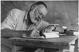 Ernest Hemingway writing on a desk