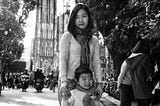 A black and white photo of a Vietnamese mom and daughter standing in a street.