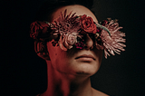 Photo of a man with his eyes covered by flowers.