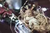 Closeup of a carved baby Jesus laying in a manger in a Nativity scene.